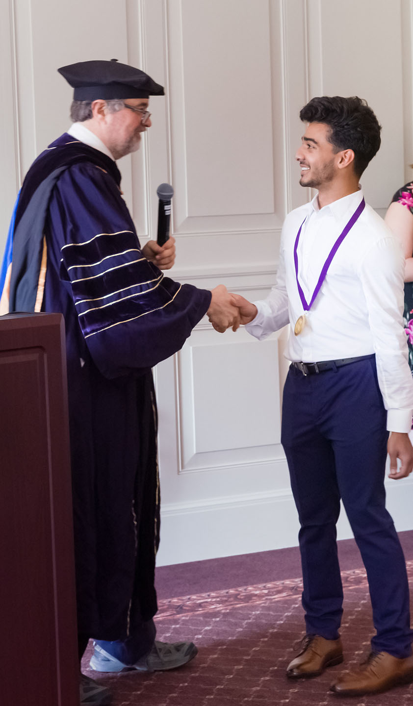 Professor and graduate shaking hands